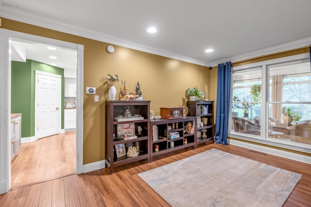 sitting room with crown molding and light hardwood / wood-style flooring