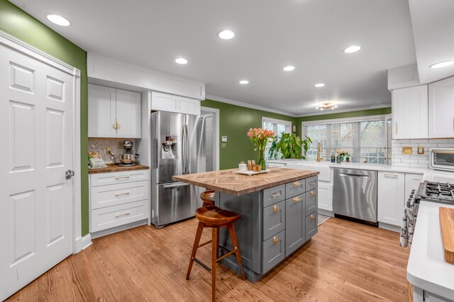 kitchen featuring gray cabinets, wooden counters, a breakfast bar, white cabinetry, and stainless steel appliances