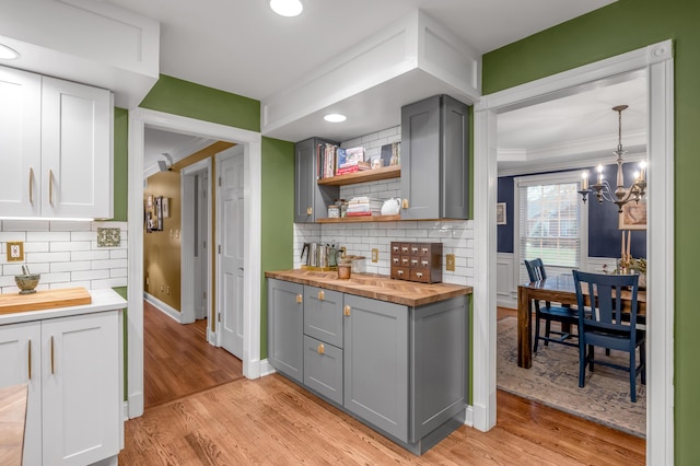 kitchen featuring tasteful backsplash, gray cabinetry, wood counters, and decorative light fixtures