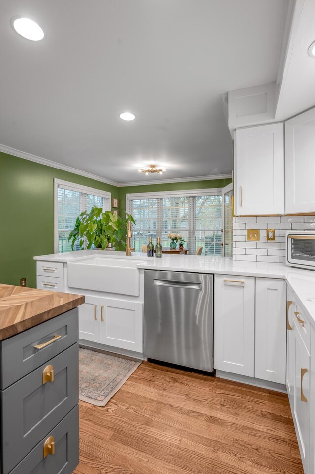 kitchen featuring sink, backsplash, white cabinets, stainless steel dishwasher, and light hardwood / wood-style floors