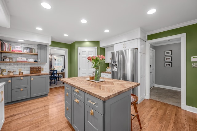 kitchen with gray cabinets, wood counters, a kitchen breakfast bar, decorative backsplash, and stainless steel fridge with ice dispenser