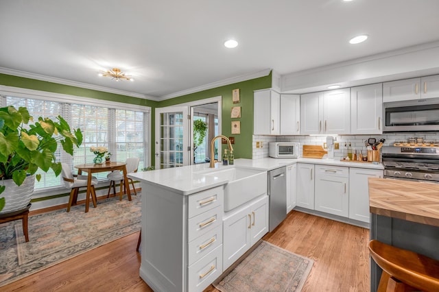 kitchen featuring sink, appliances with stainless steel finishes, light hardwood / wood-style floors, white cabinets, and kitchen peninsula