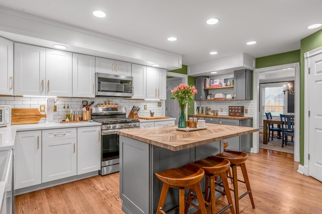 kitchen featuring a kitchen island, butcher block counters, backsplash, a kitchen breakfast bar, and stainless steel appliances