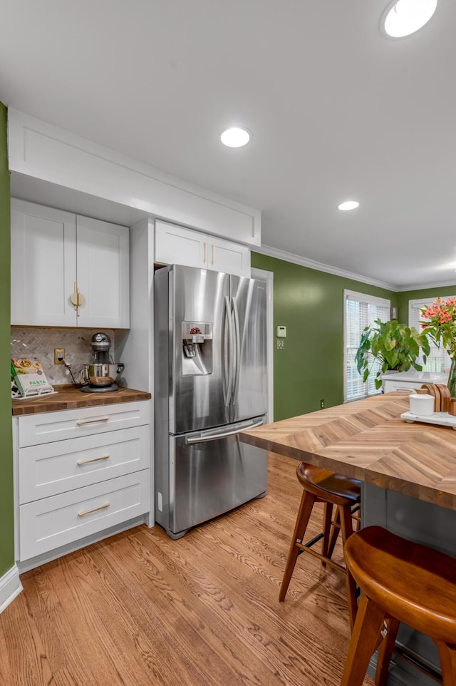 kitchen with stainless steel refrigerator with ice dispenser, white cabinets, wood counters, and light hardwood / wood-style flooring