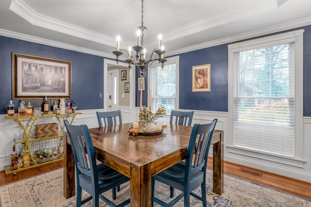 dining area featuring ornamental molding, an inviting chandelier, and light wood-type flooring