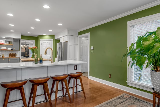 kitchen featuring stainless steel fridge, light hardwood / wood-style floors, a breakfast bar area, and plenty of natural light