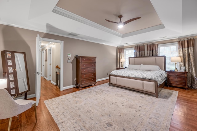 bedroom with ceiling fan, ornamental molding, a raised ceiling, and wood-type flooring