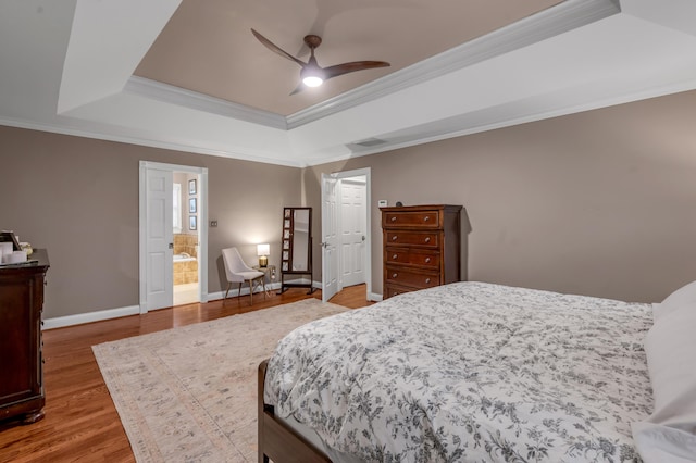 bedroom featuring a raised ceiling, hardwood / wood-style floors, connected bathroom, and ceiling fan