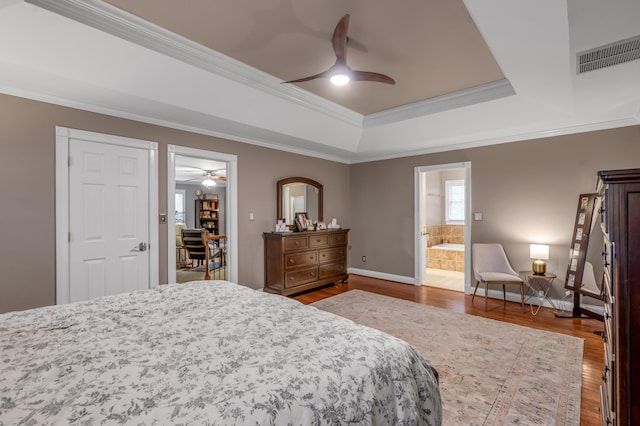 bedroom featuring hardwood / wood-style floors, connected bathroom, ceiling fan, a raised ceiling, and crown molding