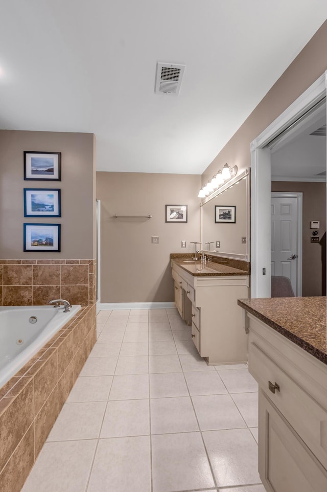 bathroom featuring tile patterned flooring, vanity, and a relaxing tiled tub