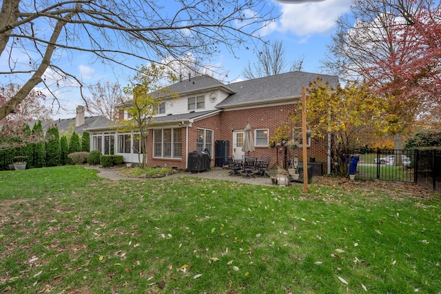 back of property with a yard, a patio area, and a sunroom