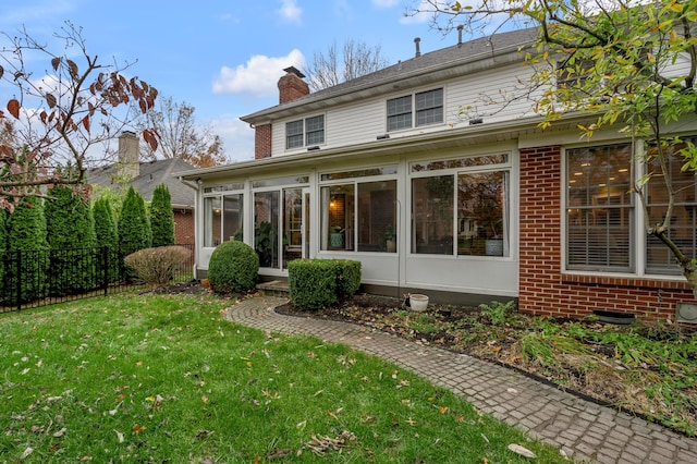 rear view of property with a yard and a sunroom