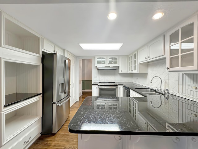 kitchen featuring appliances with stainless steel finishes, a skylight, white cabinetry, and sink