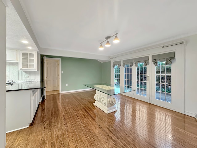 kitchen featuring decorative backsplash, white cabinets, wood-type flooring, and rail lighting