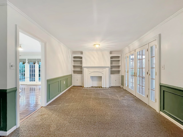 unfurnished living room with carpet, built in shelves, french doors, and crown molding