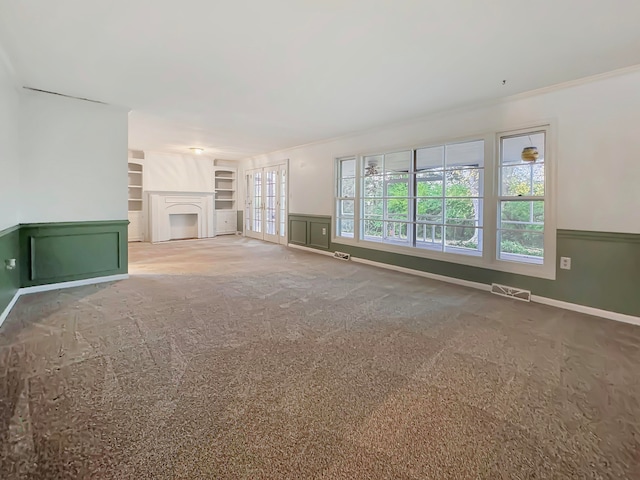 unfurnished living room with built in shelves, carpet floors, and ornamental molding