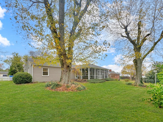 rear view of house featuring a sunroom and a lawn