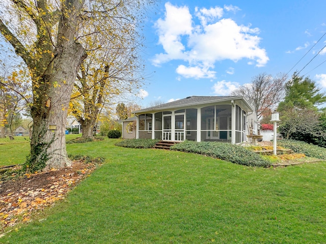 rear view of house with a lawn and a sunroom