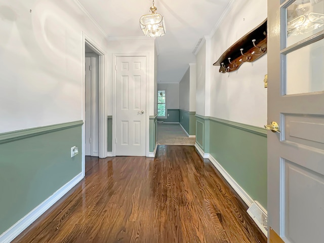 hall featuring crown molding, dark hardwood / wood-style flooring, and a chandelier