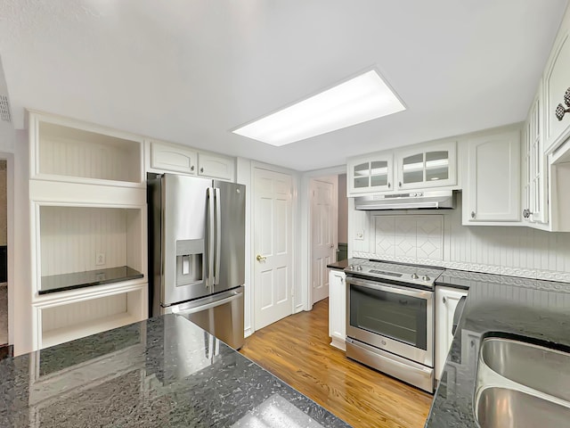 kitchen featuring white cabinetry, backsplash, dark stone countertops, light hardwood / wood-style floors, and appliances with stainless steel finishes