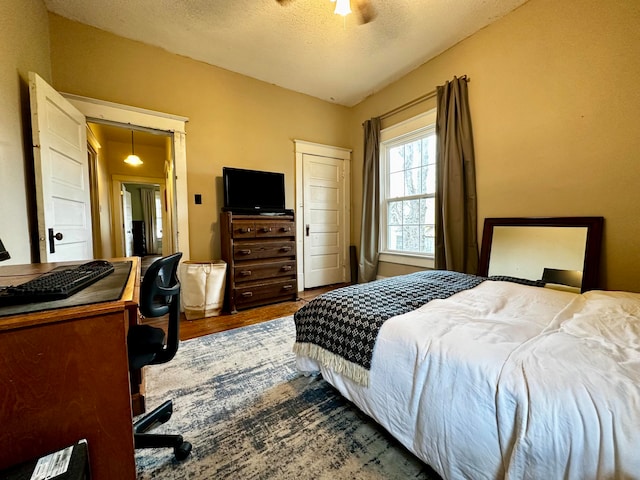 bedroom featuring ceiling fan, dark hardwood / wood-style flooring, and a textured ceiling