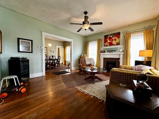 living room featuring a textured ceiling, plenty of natural light, dark wood-type flooring, and ceiling fan