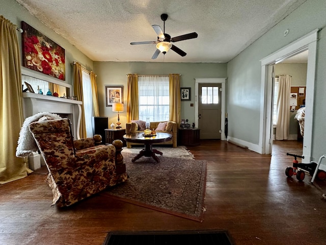 living room with ceiling fan, dark hardwood / wood-style floors, and a textured ceiling