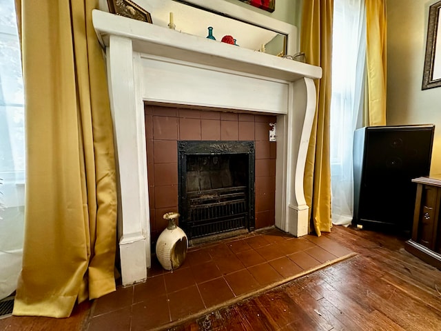 interior details featuring a tile fireplace and wood-type flooring