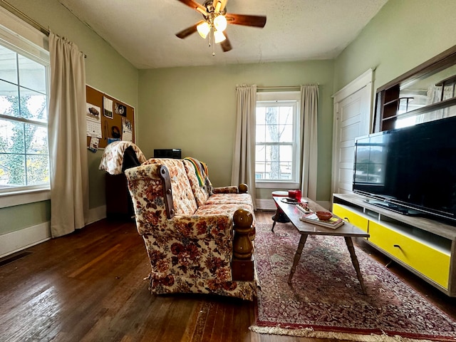 living room featuring ceiling fan, dark hardwood / wood-style flooring, and a textured ceiling