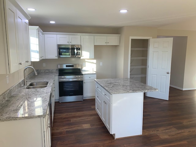 kitchen with white cabinetry, dark wood-type flooring, a kitchen island, and stainless steel appliances