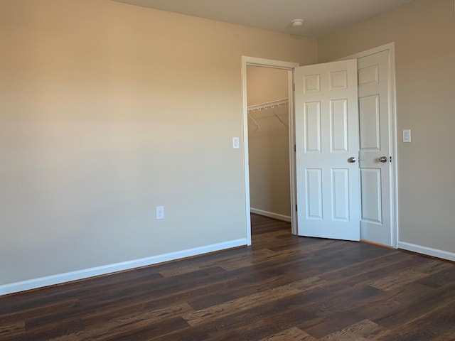 unfurnished bedroom with a walk in closet, dark wood-type flooring, and a closet