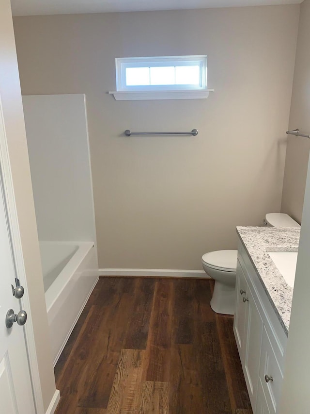 bathroom with vanity, toilet, wood-type flooring, and a tub to relax in