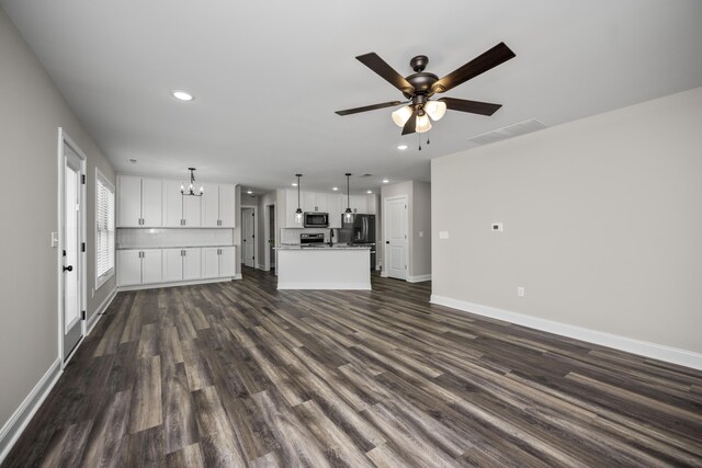 unfurnished living room with dark wood-type flooring and ceiling fan with notable chandelier