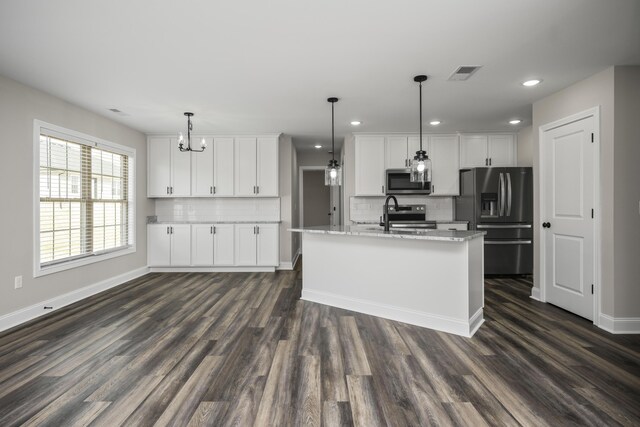 kitchen featuring dark hardwood / wood-style floors, an island with sink, white cabinets, hanging light fixtures, and stainless steel appliances