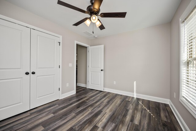 unfurnished bedroom featuring ceiling fan, dark hardwood / wood-style floors, and a closet