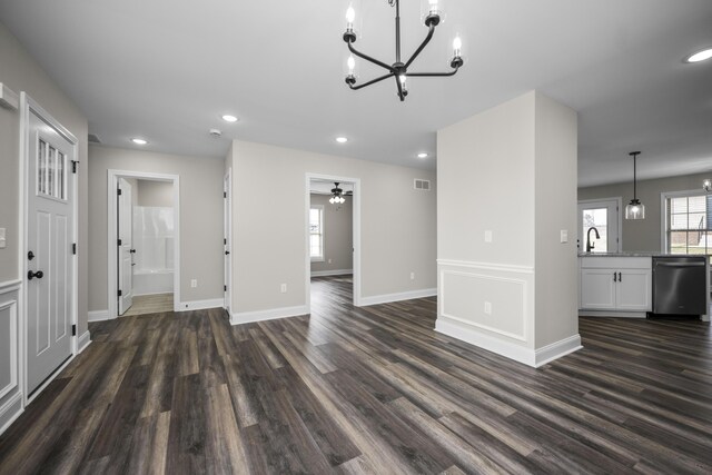 unfurnished living room with ceiling fan with notable chandelier and dark hardwood / wood-style floors