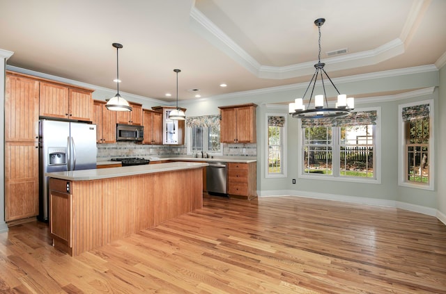 kitchen with a center island, crown molding, appliances with stainless steel finishes, and light hardwood / wood-style flooring