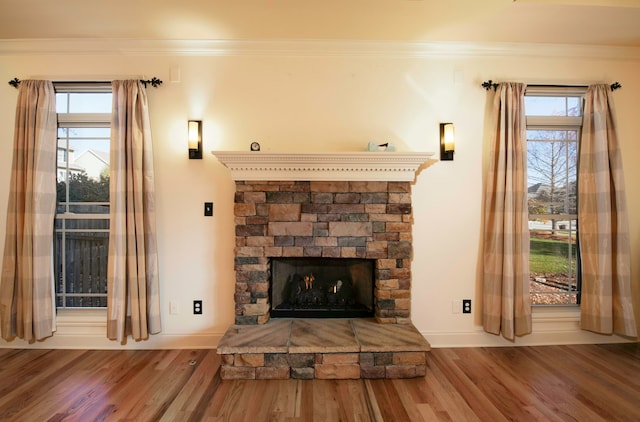 interior details featuring a stone fireplace, crown molding, and wood-type flooring