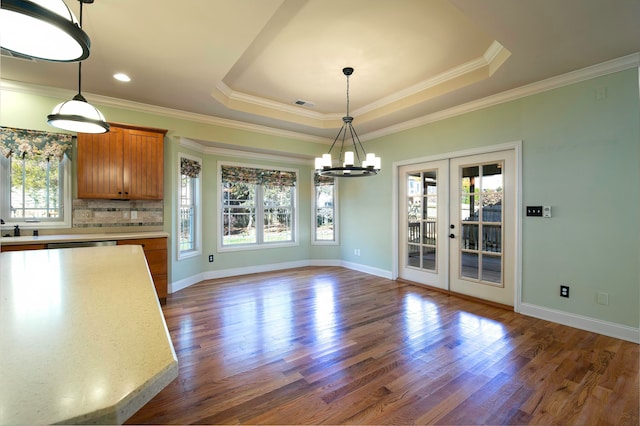 unfurnished dining area featuring a raised ceiling, dark hardwood / wood-style flooring, plenty of natural light, and french doors