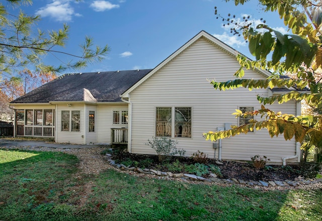 rear view of property with a lawn and a sunroom