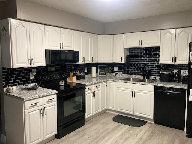 kitchen with light wood-type flooring, backsplash, sink, black appliances, and white cabinetry