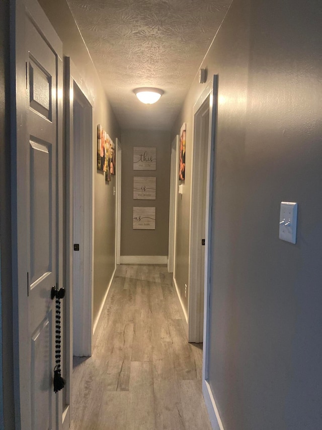 corridor featuring light hardwood / wood-style floors and a textured ceiling