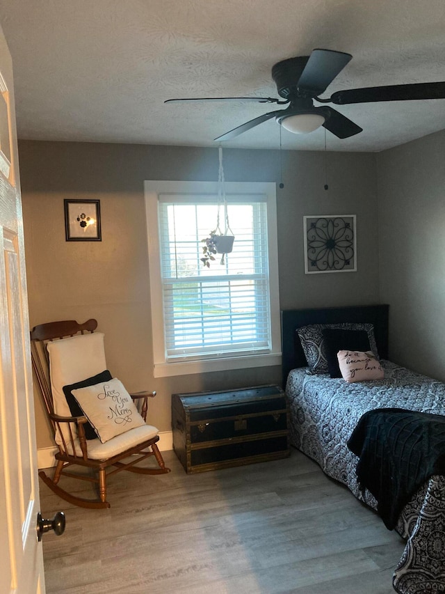 bedroom with hardwood / wood-style flooring, ceiling fan, and a textured ceiling