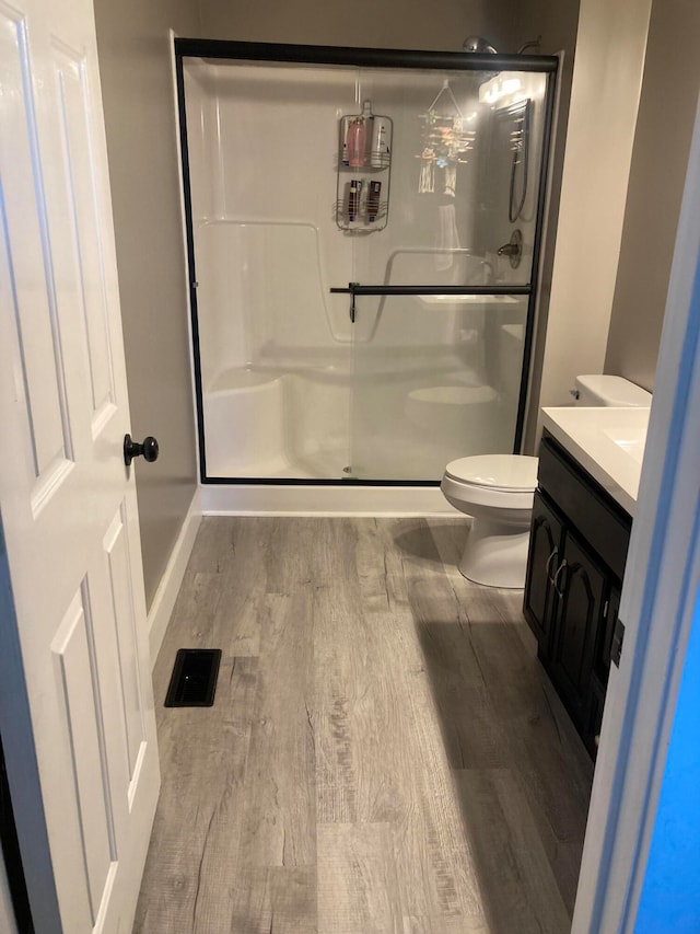 bathroom featuring hardwood / wood-style floors, vanity, toilet, and an enclosed shower