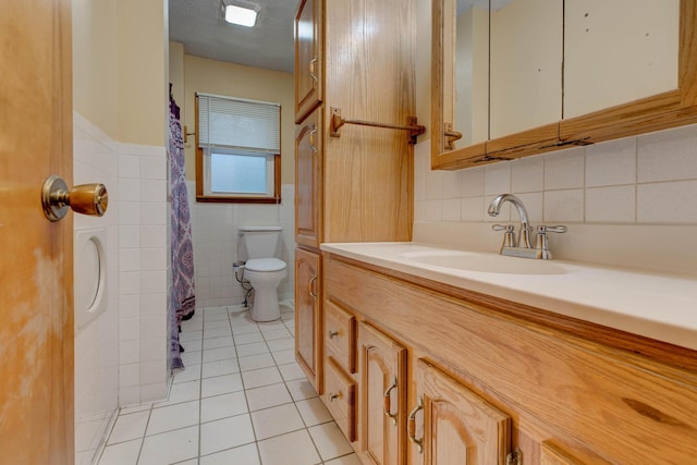 bathroom featuring a textured ceiling, vanity, tile walls, tile patterned flooring, and toilet