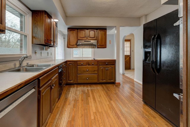 kitchen with black fridge, a textured ceiling, sink, dishwasher, and light hardwood / wood-style floors