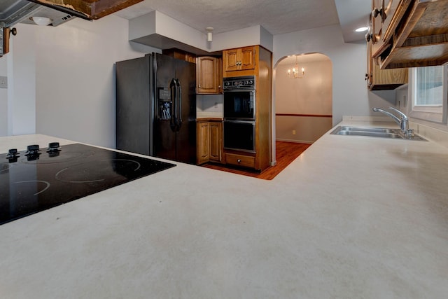 kitchen with a textured ceiling, sink, a notable chandelier, and black appliances