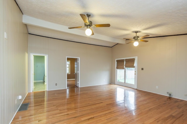 spare room with lofted ceiling with beams, a textured ceiling, and light wood-type flooring