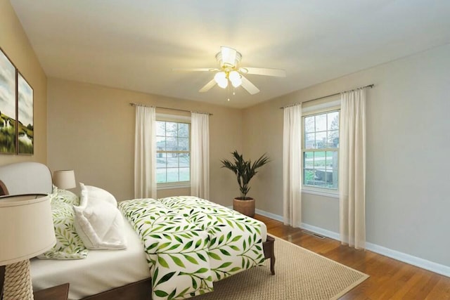 bedroom featuring ceiling fan, multiple windows, and light wood-type flooring