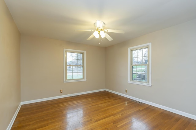 empty room with ceiling fan, a healthy amount of sunlight, and hardwood / wood-style floors